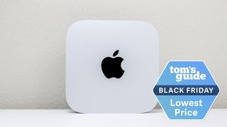 A Mac mini M4 upright on a desk with a Tom&#039;s Guide Black Friday deals badge