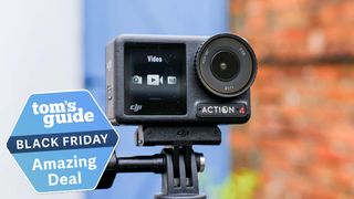 DJI Osmo Action 4 on a selfie stick against a white, blue and brick background. A Tom&#039;s Guide badge is in the lower left corner