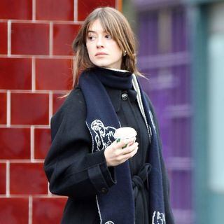 Daisy Edgar-Jones wears a black coat and carries a coffee cup