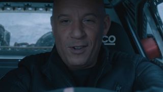 Vin Diesel driving a car and smiling in The Fate of the Furious.