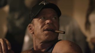 Screenshot of Taylor Sheridan&#039;s Travis smoking a cigar at poker table in Yellowstone Season 5