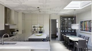 A white kitchen extension with artex ceiling and a skylight and grey kitchen island