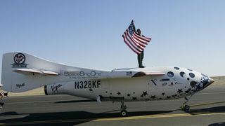 man stands on top of plane and holds the american flag