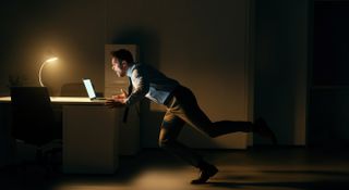 Man shouts at laptop in dark office room