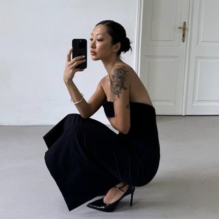 Model taking a mirror selfie wearing a black strapless Zara ZW Collection Strapless Dress and chic black heels.