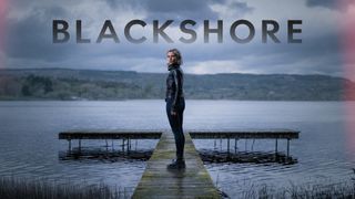 Blackshore season 1 promo picture of Lisa Dwan on a jetty with a desolate lake background. 