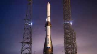 a white rocket stands on a launch pad at dusk