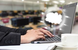 Person working at a laptop with cloud icon hovering over it