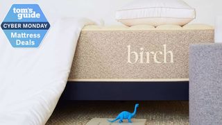 Birch Natural mattress closeup with a blue dinosaur toy at the bottom and a Tom&#039;s Guide Cyber Monday mattress deals badge in the top left