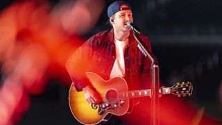 Morgan Wallen playing guitar and singing as he performs at the Billboard Music Awards