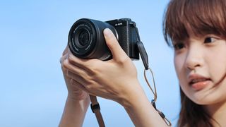 Woman holding a Fujifilm camera with a Viltrox AF 35mm f/1.7 attached