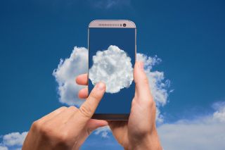 A person tapping a smartphone with a cloud on the screen.