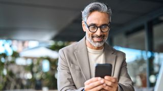 a silver-haired gentleman looks happily at his smartphone