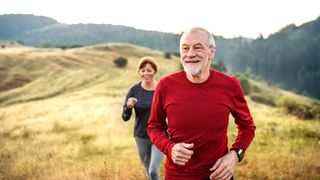 Senior couple trail running outdoors in nature in the foggy morning