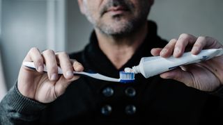 a man puts toothpaste on a toothbrush