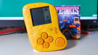 McDonald&#039;s McNugget handheld sitting on white desk next to copy of Tetris for Game Boy