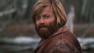 Robert Redford with a huge beard, smiling in Jeremiah Johnson