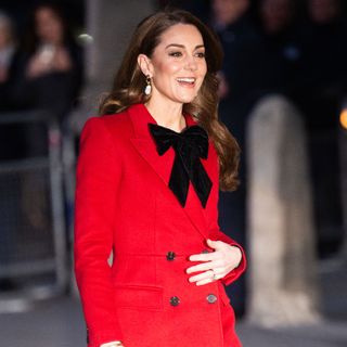 Kate Middleton wears a black bow and a red coat