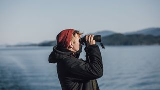 Man holding one of the best binoculars for long distance viewing to his face