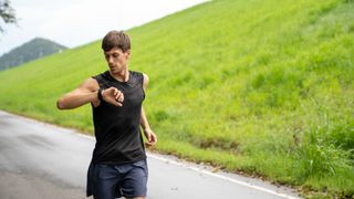 A male runner is checking one of the best running watches while exercising