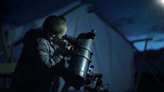 A child using one of the best telescopes for kids outside while camping