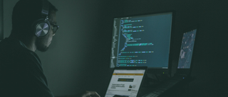 Man using a laptop and computer in a darkened home office