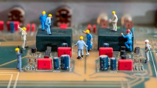 A close up photo of a computer motherboard with miniature figures of workmen placed on top, to represent the right to repair.