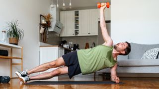 Man performing a side plank with lateral raise at home