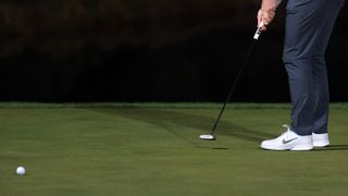 The legs of a golfer with a golf ball in the foreground