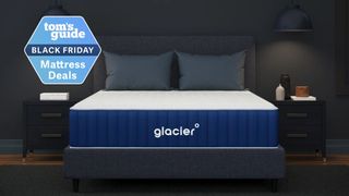 Navy and white Glacier mattress on dark grey bed base with two grey pillows in dark room with two wall-mounted lamps either side.