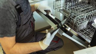 A plumber installing a dishwasher