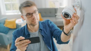 Man setting up home security camera with smartphone