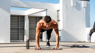 Man performing a plank with one leg raised during bodyweight workout on exercise mat outdoors