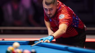 Mosconi Cup 2024 USA captain Skyler Woodward gets down to play a shot on a blue 9-ball pool table ahead of the Mosconi Cup live streams around the world, starting Nov. 30