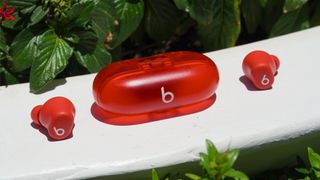 The transparent red Beats Solo buds on a ledge.