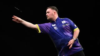 Luke Littler of England, wearing purple shirt with yellow accents on the sleeves, throws a dart ahead of his assault on the 2025 PDC World Darts Championship 