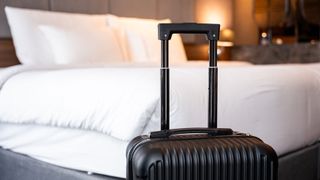 A suitcase in front of a mattress in a luxury hotel room