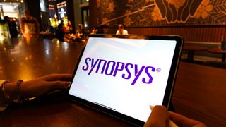 Synopsys logo in purple lettering pictured on a tablet screen with restaurant in background.