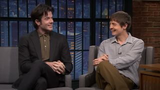 John Mulaney and Simon Rich chatting and laughing while being interviewed on Late Night with Seth Meyers