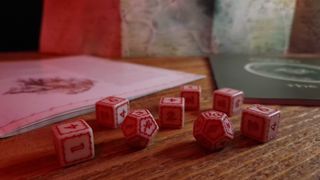 The One Ring Starter Set dice in the foreground, with a book and map in the background