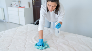 A woman cleaning up a spill on a mattress