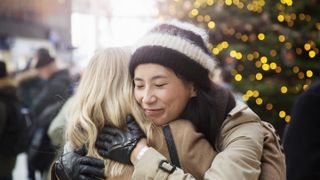 women hugging by christmas tree