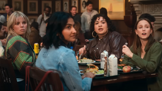 Renée Rap, Amrit Kaur, Ilia Isorelys Paulino, and Pauline Chalamet gathered around the dinner table, all checking out a boy in The Sex Lives of College Girls Season 3