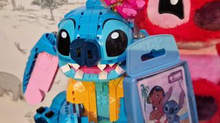 Lego Stitch beside a large plush toy, and a Top Trumps case