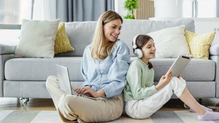 Mom and daughter watching at their devices in the living room 