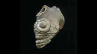 Clay pipe whistle shaped like a skull against a black background