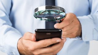 Man using a magnifying glass to look at a smartphone