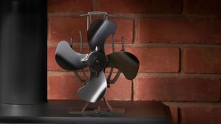 A stove fan stood on a stovetop in front of a brick wall