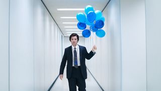 A still from a promo image for the second season of Severance showing the character Mark holding blue balloons in a hallway