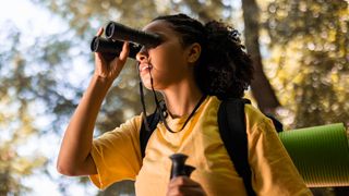 Woman using binoculars in a forest